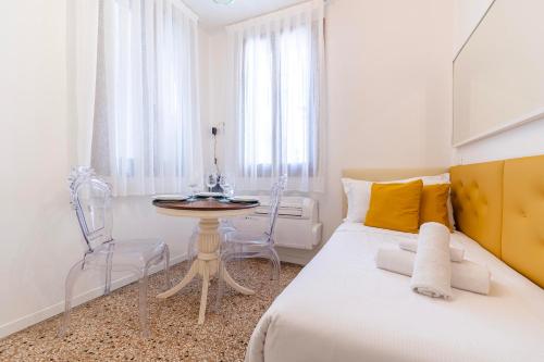 a white bedroom with a bed and a table at Rigoletto Apartments by Fenix in Venice