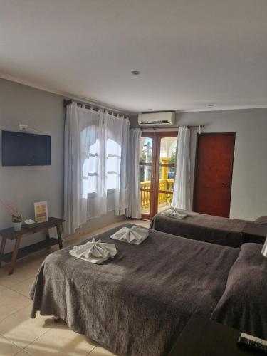a bedroom with two beds and a table and a window at Hotel Maspalomas in Villa Carlos Paz