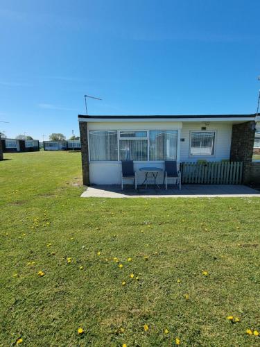 a house with a table and chairs in a yard at Sands Holiday Chalet Dog friendly, free wifi, swimming pool and new gym passes and free club entry in Scratby
