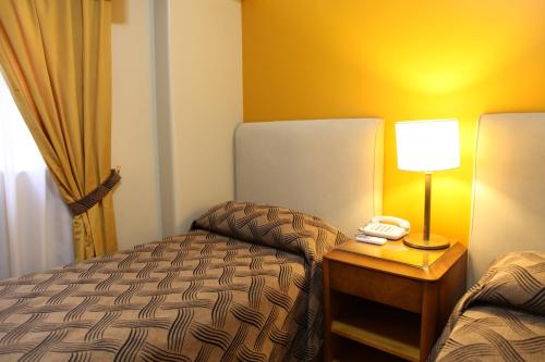a hotel room with a bed and a lamp on a table at Tritone Hotel in Buenos Aires