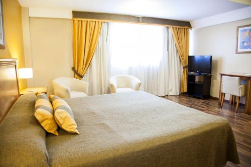 a hotel room with a large bed with yellow pillows at Tritone Hotel in Buenos Aires