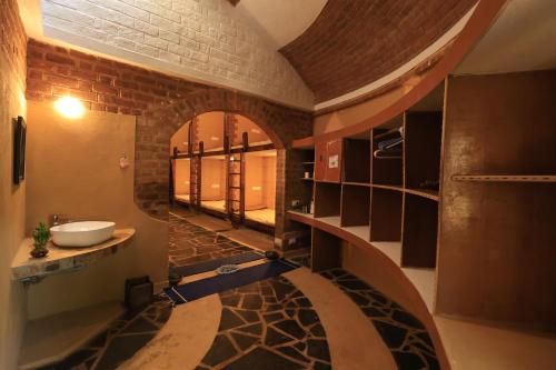 a bathroom with a sink in a room with a brick wall at Surwahi Social Ecoestate Kanha in Kānha
