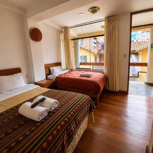 a hotel room with two beds and a window at Killaqente in Cusco