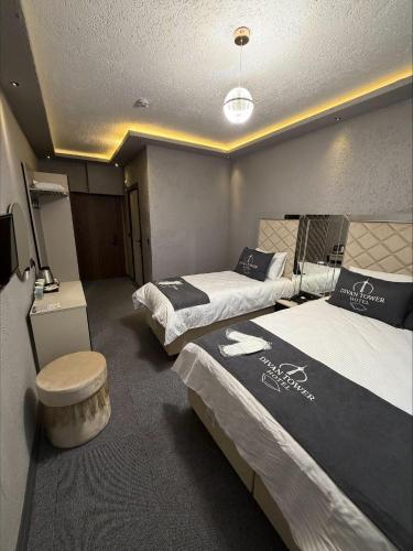 a room with two beds and a stool in it at Divan Tower Otel in Erzurum