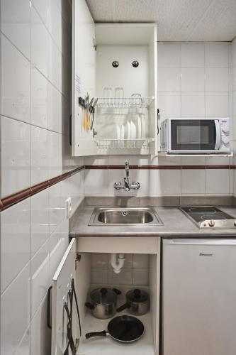a small kitchen with a sink and a microwave at Apartamentos Resitur in Seville