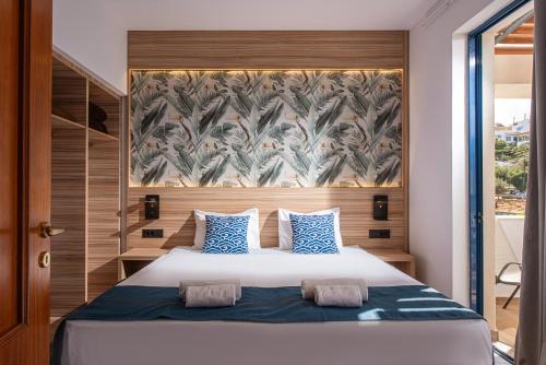 a bedroom with a large bed with blue and white pillows at Eleni Beach Apartment in Stalís