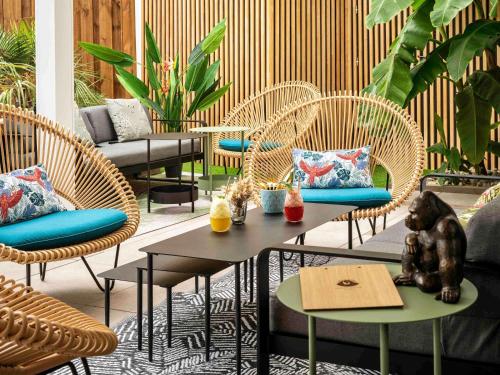 a patio with wicker chairs and a table with dolls on it at Mercure La Roche Sur Yon in La Roche-sur-Yon