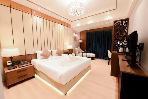 a bedroom with a large white bed and a television at Avinash International in Jagdalpur