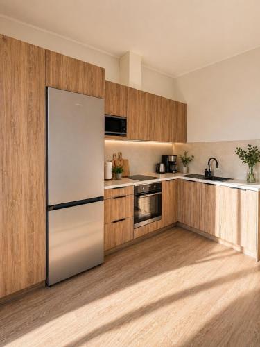 a kitchen with a white refrigerator and wooden cabinets at Guest House Klevu 17 in Palanga