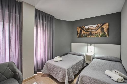 a hotel room with two beds and a chair at Apartamentos Resitur in Seville