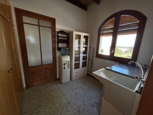 a bathroom with a sink and a refrigerator and a window at L'Estança de Can Rodó in Vilobí d'Onyar