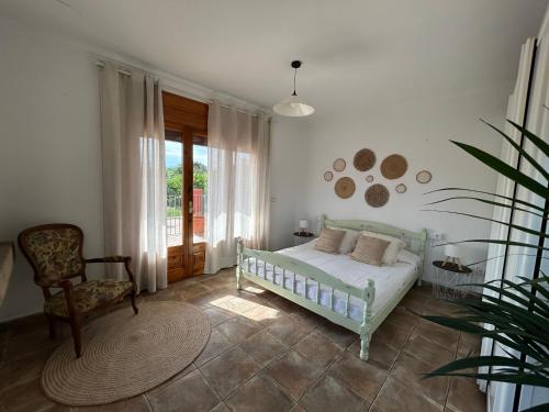 a bedroom with a bed and a chair and a window at L'Estança de Can Rodó in Vilobí d'Onyar