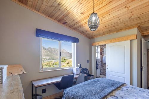 a bedroom with a bed and a desk and a window at New Mountain Retreat with Scenic Views in Hout Bay