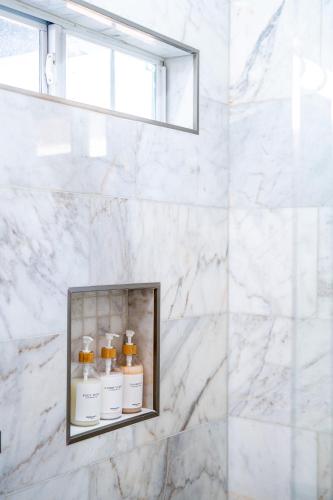 a bathroom with three bottles of moisturizers on a shelf at Southtown 3BR Cowboy Pool, Playset, Riverwalk, BBQ, Firepit, Big Yard — Downtown San Antonio in San Antonio