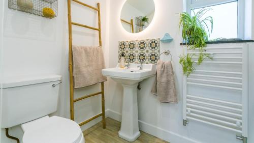 a bathroom with a sink and a toilet and a mirror at Pen Lon Quirt in Newborough