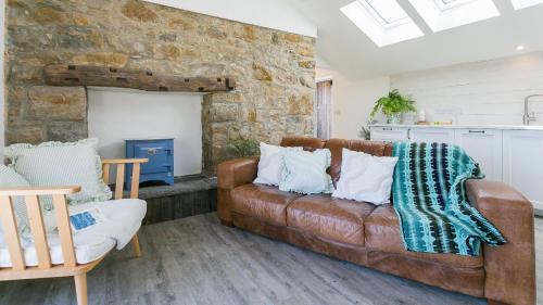 a living room with a brown leather couch at Pen Lon Quirt in Newborough