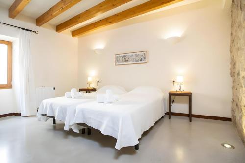 two beds in a white room with two tables at Ca Sa Padrina in Artá