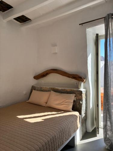 a bed in a white room with a window at Mikro Kastro in Amorgos
