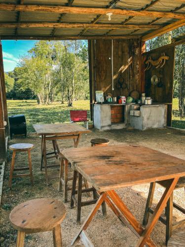 two picnic tables and stools in front of a cabin at Camping Rio do Rastro in Lauro Müller