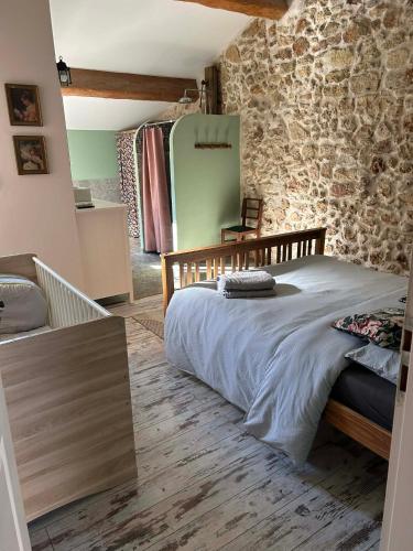 a bedroom with a bed and a stone wall at L'Amandine in Puisserguier