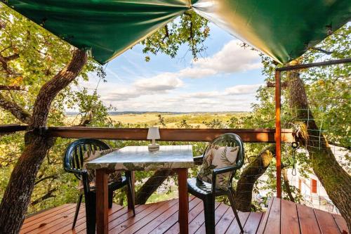 a table and chairs on a deck with a tree at B&B La Cabane Insolite in Monès