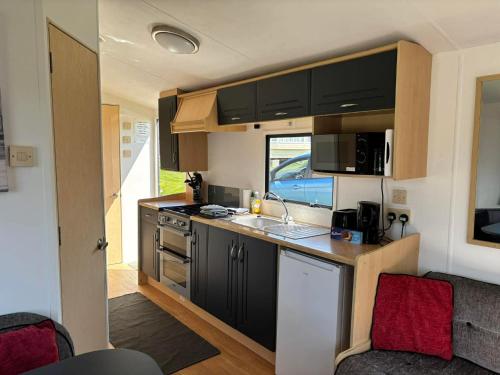 a kitchen with black cabinets and a sink in a caravan at Cornish Dreams - WiFi in Newquay