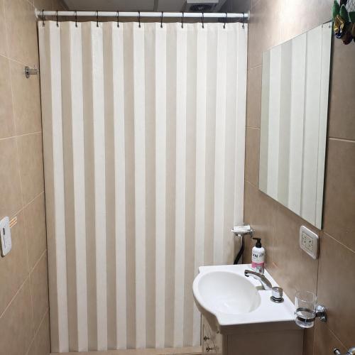 a bathroom with a sink and a shower curtain at La Quilmeña Esquel centro in Esquel