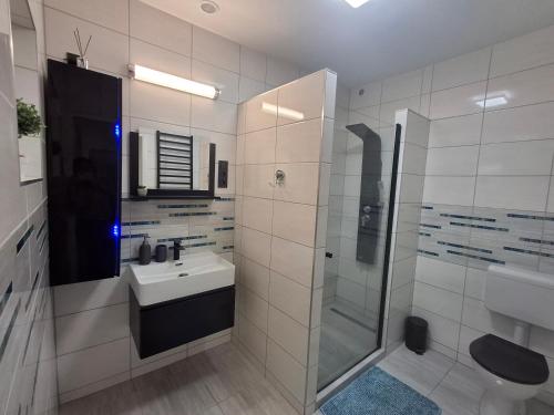 a white bathroom with a sink and a shower at MOONLIGHT Prémium APARTMANHÁZ in Sárospatak