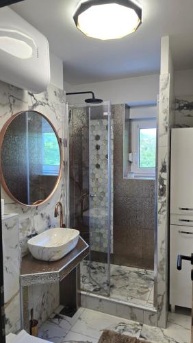 a bathroom with a sink and a shower with a mirror at Apartman NIKOL in Senj
