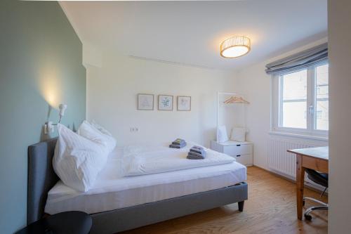 a bedroom with a bed and a desk and a window at Modernes Ferienhaus Dornbirn mit 2 Schlafzimmern 2 Bädern nahe Bodensee & Bregenzerwald in Dornbirn