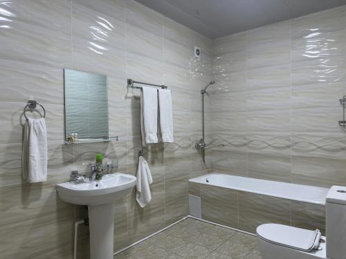 a bathroom with a sink and a tub and a toilet at Art Angren Hotel in (( Sotsgorod ))
