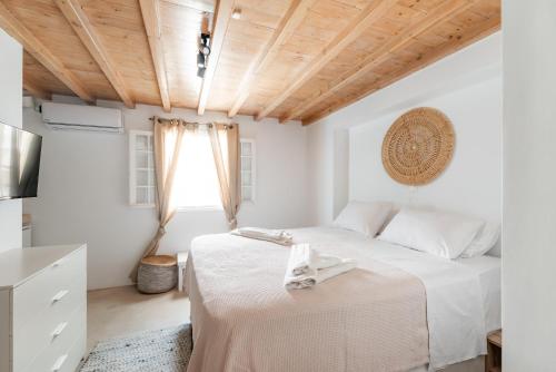 a white bedroom with a bed and a window at White Pearl Mykonos in Mikonos