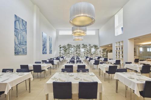 a dining room with white tables and blue chairs at Grace Smart Design Hotel - "Hotel Anjo de Portugal" in Fátima