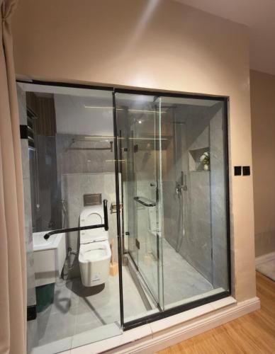 a bathroom with a glass shower and a toilet at Premium 2 Bedroom Maisonette with Ps5 & Pool in Lekki