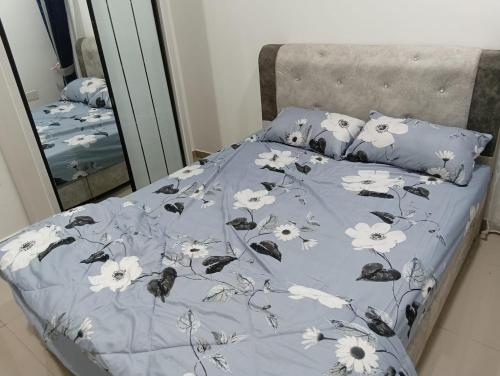 a bed with a blue comforter with flowers on it at SD Homestay in Bachok