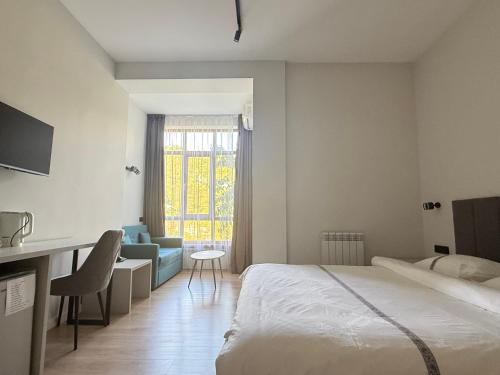 a bedroom with a bed and a desk and a chair at Green Hill Hotel in Almaty