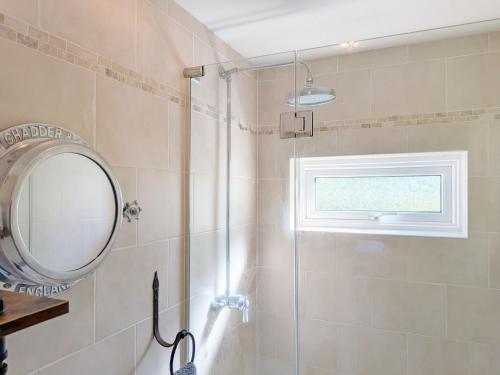 a bathroom with a shower with a mirror and a window at Springwell , West Wittering in West Wittering