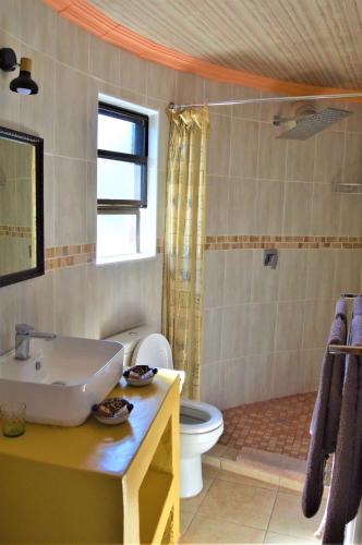a bathroom with a white toilet and a sink at Crocodile Pools Resort in Gaborone