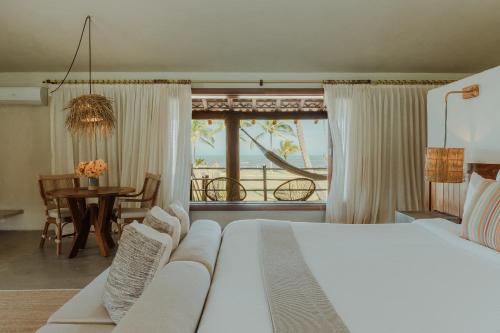 a bedroom with a white bed and a table with a view at Reserva Jacumã Boutique Hotel in Trancoso