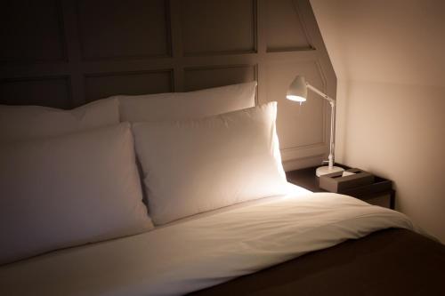a bedroom with a bed with white pillows and a lamp at Hotel Gaden in Suwon