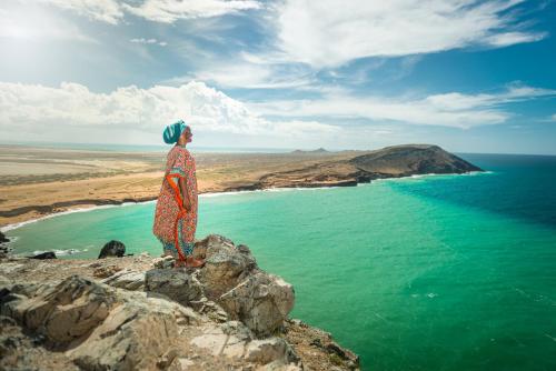 a woman standing on a cliff overlooking the ocean at Hotel Waya Guajira By OxoHotel in Albania