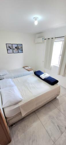 two beds in a white room with a window at Loft central, cozinha e sala in Joinville