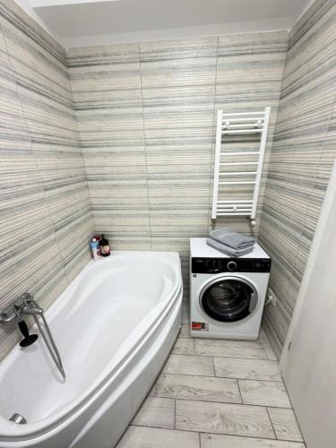 a bathroom with a tub and a washing machine at RC RelaxApart 15 in Dudu