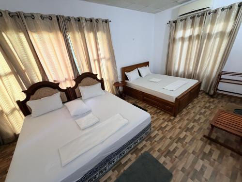 a bedroom with two beds and two windows with curtains at Green Senz - Tourist Board Approved Hotel & Hostel - Sigiriya in Sigiriya