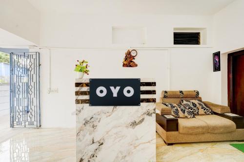 a living room with a couch and a sign on the wall at Hotel O Sky Blue Residency in Chennai