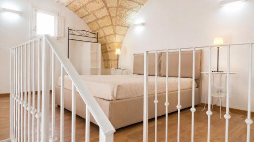 a white bedroom with a bed and a staircase at Corte Nizza in Taviano