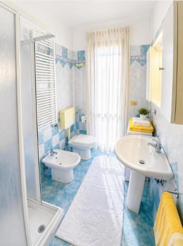 a blue and white bathroom with a sink and a toilet at Residence Pineta - Agenzia Cocal in Caorle