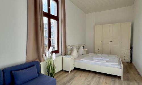 a bedroom with a white bed and a blue chair at Villa Pippingsburg am Strand in Ahlbeck