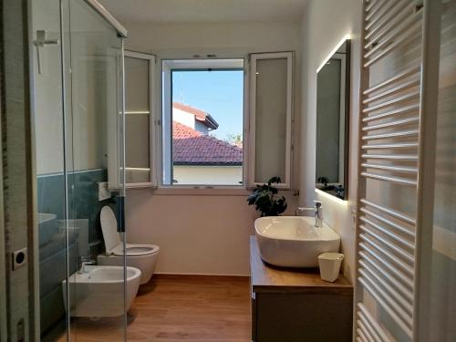 a bathroom with a sink and a toilet and a window at La Papessa in Savio di Ravenna