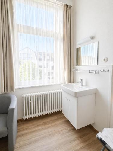 a white bathroom with a sink and a window at Pension Haus Weierts in Norderney